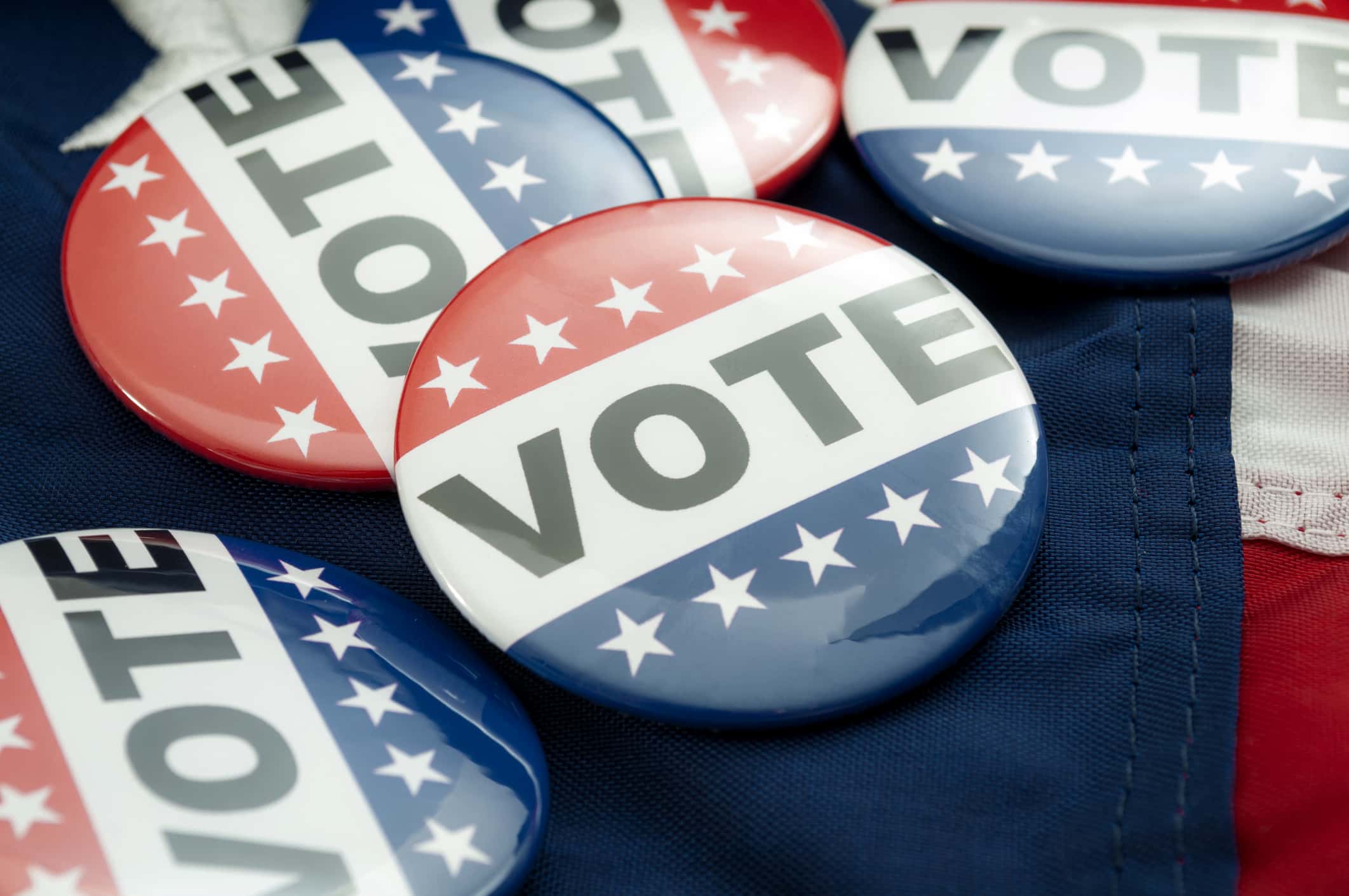 A pile of red, white, and blue buttons with the word “Vote”